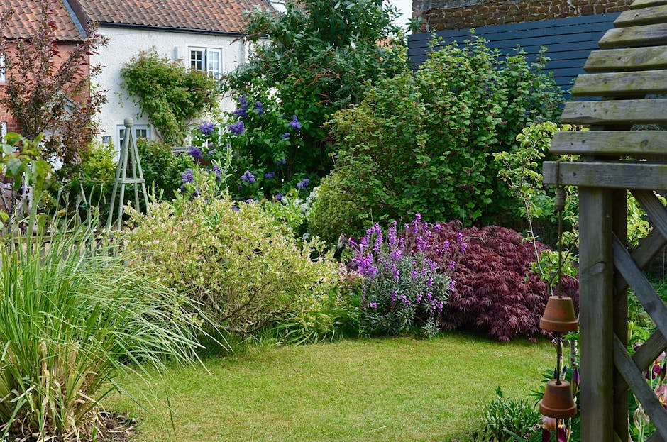A charming garden pathway leads to a vibrant blue front door marked with the number 55, set within a white arched doorway surrounded by lush greenery. Overgrown ivy and leafy shrubs frame the entrance